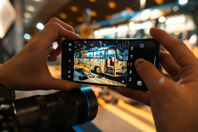 Hands holding smartphone taking picture of bus.